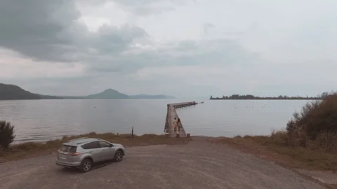Drone footage of couple walking down jetty together at Tokaanu Wharf Stock Footage 106738324