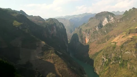 Drone footage of a deep valley with emerald river in between mountains Ha Giang Video stock 313798402