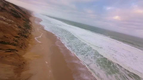 Drone footage displays dramatic coastline with cliffs, beaches, and foamy waves Video stock 345149105