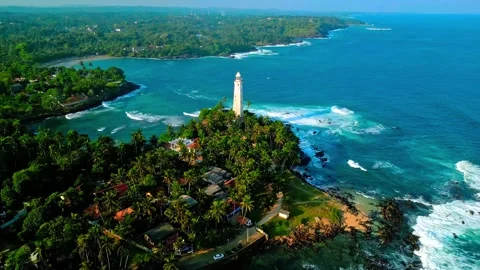 Drone footage of Dondra Head lighthouse on rocky peninsula surrounded by Stock Footage 344240802