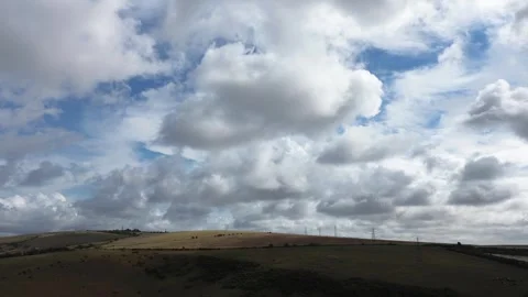 Drone footage of dramatic cumulus clouds filling a vast blue sky above rolling Video stock 345773802