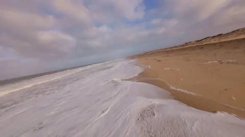 Drone footage flies low over wet sand, showing waves meet shore Stock Footage 345149384