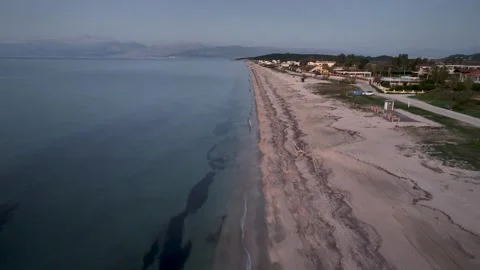 Drone footage flying over a long, tranquil sandy beach and calm sea at twilight Stock Footage 319652272