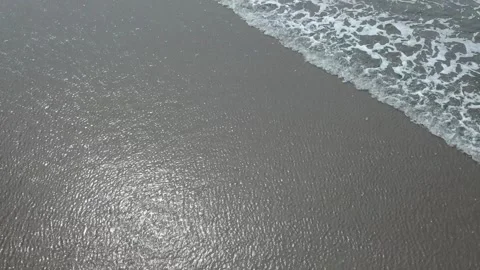 Drone footage flying over waves on a beach. Camera moves slowly over water. Stock Footage 228629627