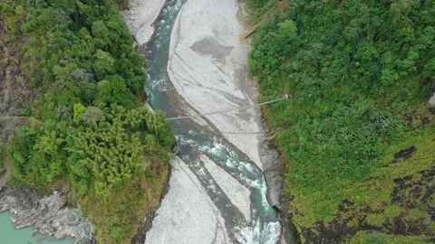 The drone footage of forest and flowing river with hanging bridge over it. Stock Footage 134285857