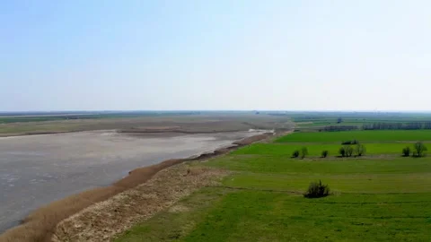 Drone footage of green fields surrounding a lake in nature reserve Slano Kopovo Stock Footage 270501948