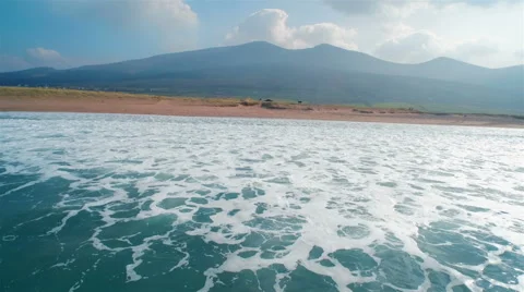Drone footage of ocean waves reaching shore against mountains Stock Footage 50169113