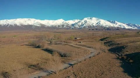 Drone footage of a road winding through a snowy mountain landscape Stock Footage 277962876