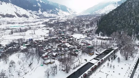 Drone footage showcasing snow-covered lanes and traditional homes of Verinag Stock Footage 311129316