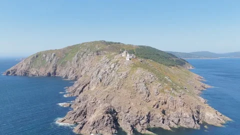 Drone footage shows the Faro de Fisterra lighthouse perched on a rugged, rocky Stock Footage 346718853