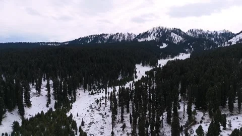 Drone footage of a stream snaking gracefully through snow in Dhoodhpathri’s Stock Footage 311794039