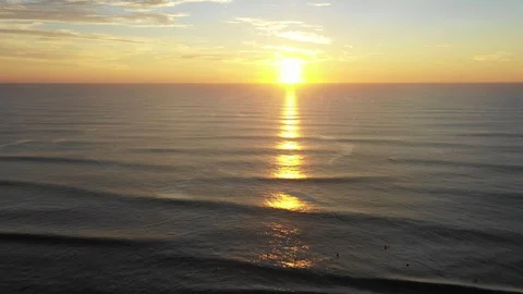 Drone footage of surfers on the water at sunrise Stock Footage