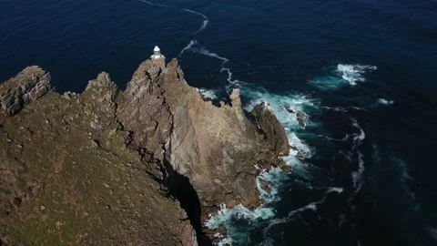 Drone footage of tiny lighthouse on a rocky cliff tin the ocean 動画素材 221193594