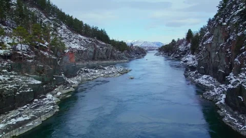 Drone footage of turquoise river flowing through snowy mountain canyon. Video stock 344995817