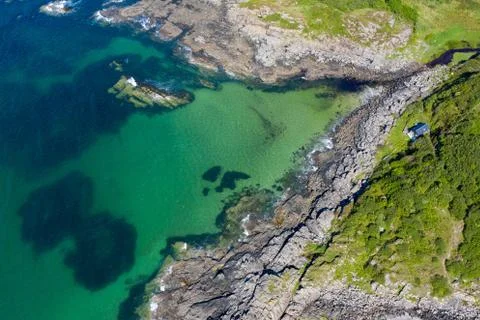 Drone footage of waves lapping up onto rocks in Portuairk Bay, Scotland Stock Photos
