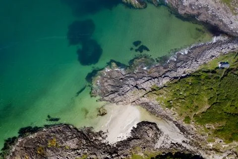 Drone footage of waves lapping up onto rocks in Portuairk Bay, Scotland Stock Photos