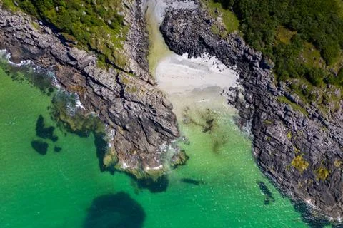 Drone footage of waves lapping up onto rocks in Portuairk Bay, Scotland Stock Photos