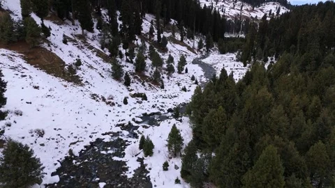 Drone footage of a winding stream weaving through snowy white landscapes in Stock Footage 311793833