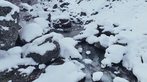 Drone forward flight over glacial steam in snow covered boulders Stock Footage 328961009