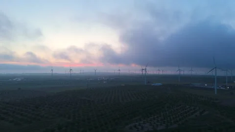 Drone forward flight over wind turbines and agricultural fields at dawn Stock Footage 308221418