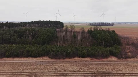 Drone forward flight over winter fields and forest with wind turbines Stock Footage 335052618