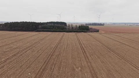 Drone forward flight over winter agricultural field with wind turbines Stock Footage 335052639