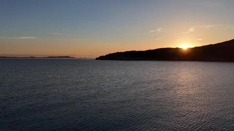 Drone Forward Flight Into Sunrise Behind Coastal Hill Over Peaceful Beac Stock Footage 334854514