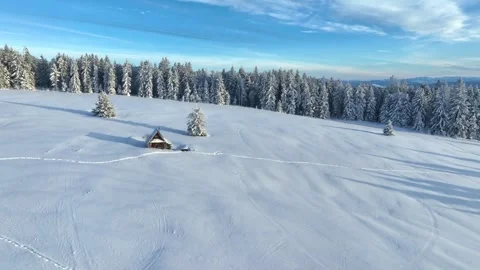 Drone forward flight towards rustic wooden cabin in snowy mountains Stock Footage 336384473