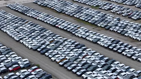 Drone forward flyover above massive vehicle storage lot with rows of new cars Stock Footage 340603982