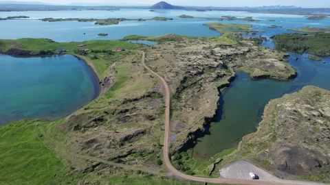 Drone forward pan over lava formations, lakes and gravel road at Myvatn Stock Footage 346552176