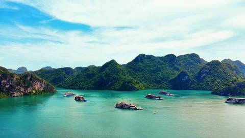 Drone forward push past luxury cruises toward towering karst cliffs 4K Stock Footage 340744061