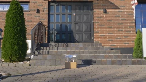 Drone in front of a house pick up package and fly away Stock Footage 82430764