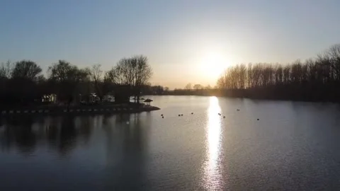 Drone glide over water toward sun reflection, rising to sunset Video stock 331851036