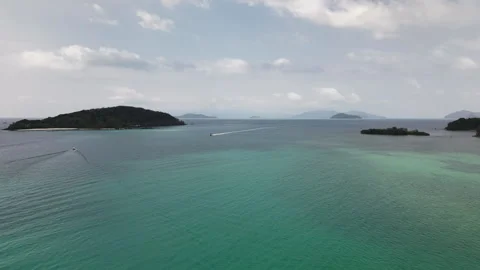 Drone glides above clear turquoise sea near tropical island as boats speed Stock Footage 309192480