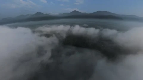 Drone glides above thick clouds, revealing distant mountain peaks Stock Footage 339833300