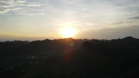 Drone glides over forest trees toward the sunset above Cat Ba National park in Stock Footage 317223387