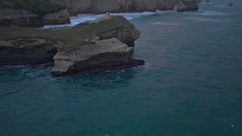 Drone glides past the dramatic sea cliffs of Tunnel Beach at sunrise in Stock Footage 340149263