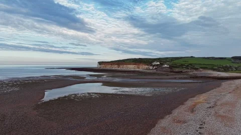 Drone gliding along layered beach with soft waves and scenic cliffs Stock Footage 309765164