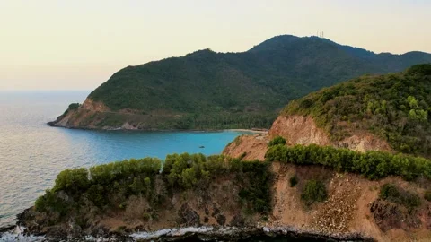 Drone gliding past sea cliffs towards a hidden beach in Nam Du 4K Stock Footage 333939020