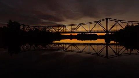 Drone going over river orange sunset with bridge in background Stock Footage