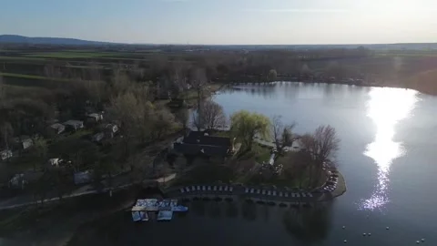 Drone half-orbit around island with sun reflection on lake Video stock 331850792