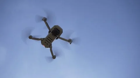 Drone Hangs in the Air. Blue Sky, View from Below. Landing drone with a camera Stock Footage 238525524