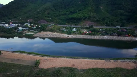 Drone high-angle shot flying over a wide river reflecting green hills Stock Footage 336610427