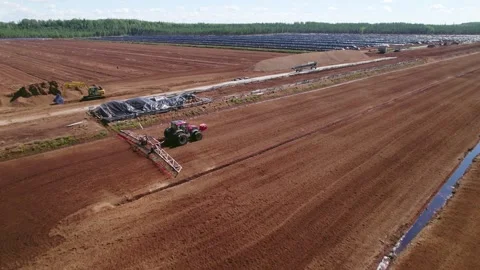 Drone High Angle View of Tractor Racing Across Peat Field Preparing Uniform Rows Stock Footage 294687796