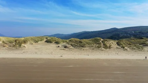 Drone hises high over the beach and sand dunes near the Welsh town of Harlech Stock Footage 107936517