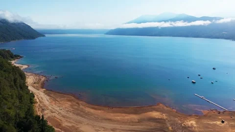Drone Horizontal Panning Shot of a Wide Sandy Beach, Blue Lake Water and Fo.. Video stock 339252245