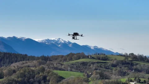 Drone hovering above green hills with snow capped Pyrenees mountains in Stock Footage 337959329