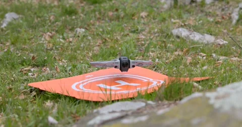 Drone Hovering Above Orange Landing Pad on Green Grass Stock Footage 343929141
