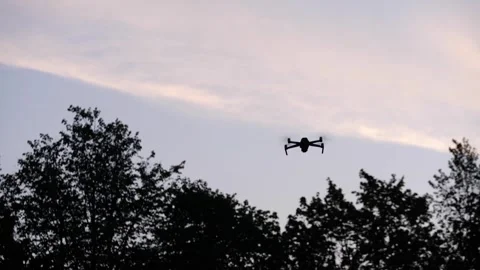 The drone hovering in the air and then quickly flies forward, with dark trees Stock Footage 314483313