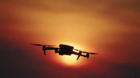 A drone hovering and slowly descends against a vibrant orange and red sunse.. Stock Footage 335013457